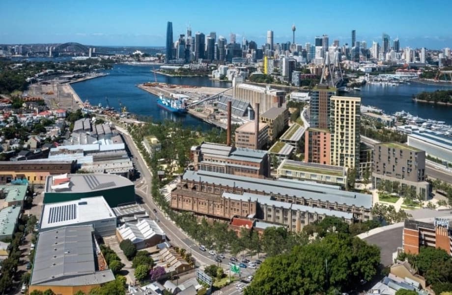 Aerial render showing the full scale of the Bays West precinct along Sydney Harbour, with residential towers and green rooftops.