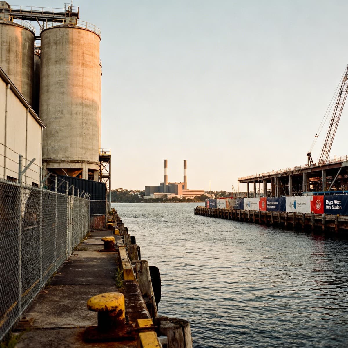 Current Glebe Island site with industrial silos, Bays West Metro Station construction in the background, and harbour waterfront.