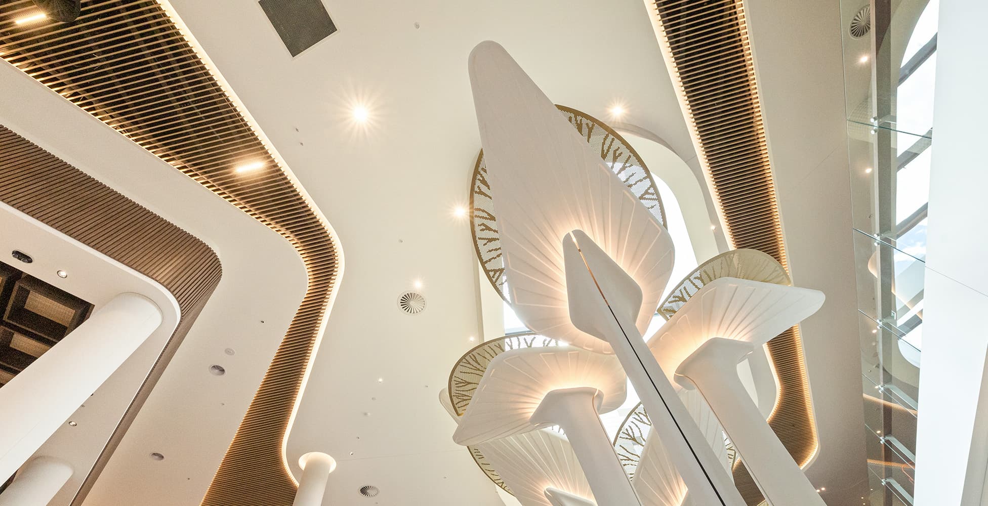 The dramatic sculptural light installation in the main atrium, with organic leaf-like forms rising through a double-height void — one of the signature interior design moments of the resort.