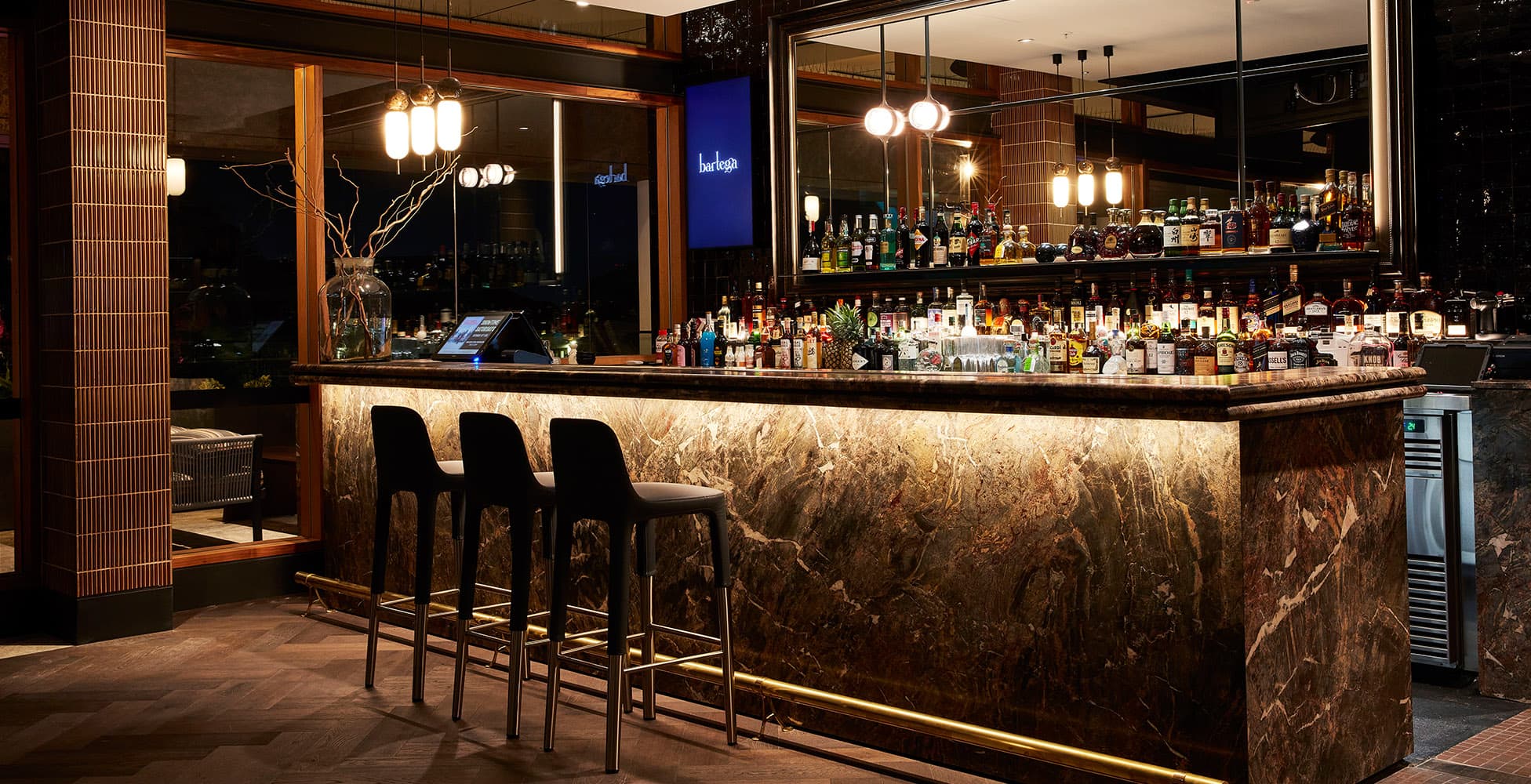 Bartega cocktail bar at Canterbury League Club, featuring a dark marble bar counter, pendant lighting, and a premium spirits display — designed by Altis Architecture and built by Calida Projects.