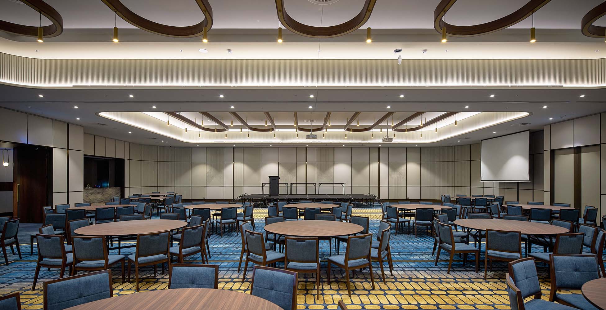 The new 500-seat auditorium configured for a banquet event, showing the subdivided function space with operable walls, timber ceiling battens, and integrated AV.